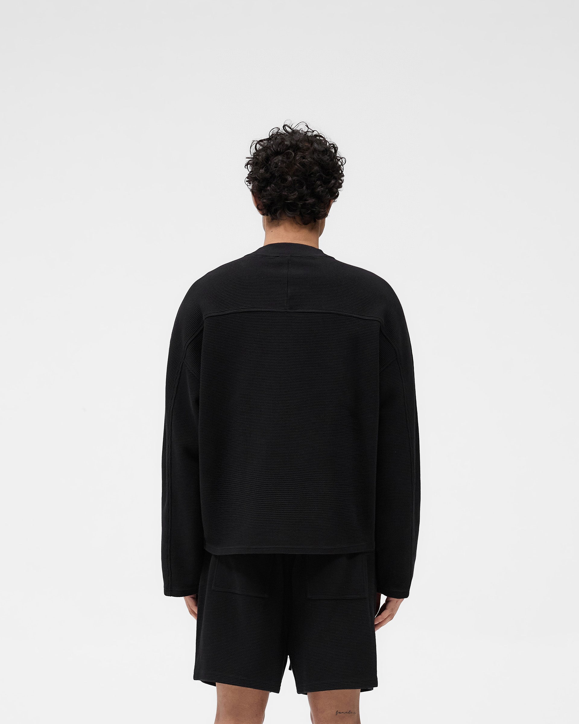 Man wearing a black long sleeve t-shirt on a plain white background | Waffle Long Sleeve T-Shirt in Black | Boxy fit waffle fabric long sleeve t-shirt | SS25 T-Shirts | Represent Clo
