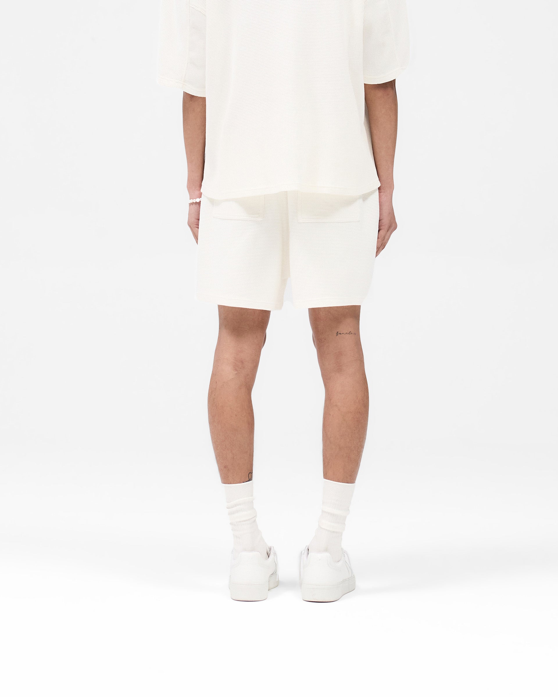 Man wearing white shorts on a plain white background | Waffle Shorts in White | Heavyweight waffle fabric shorts with elasticated waistband | SS25 Shorts | Represent Clo