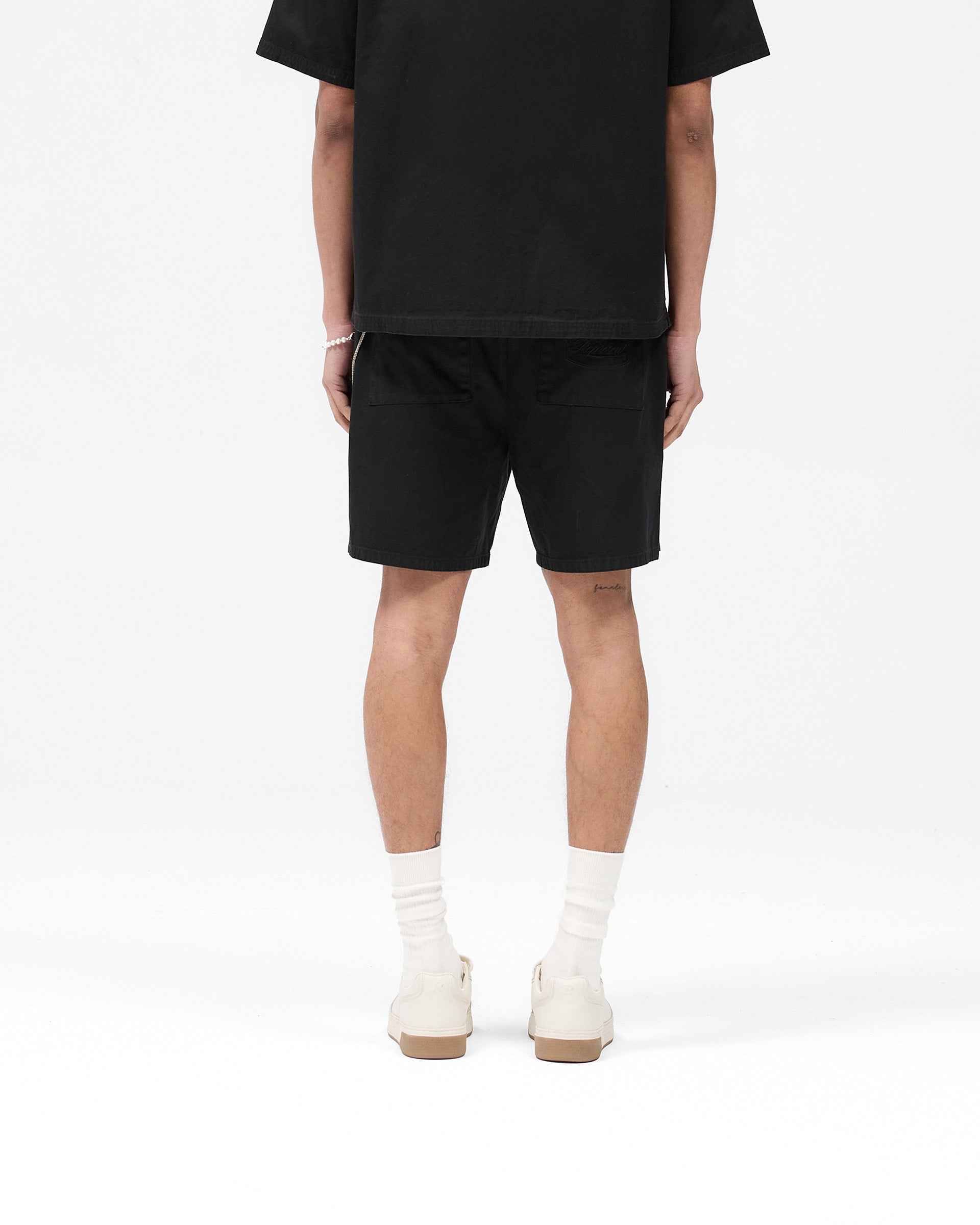 Man wearing black tailored shorts on a plain white background | Cotton Tailored Short in Jet Black | Structured fit shorts with belt loops | SS25 Shorts | Represent Clo