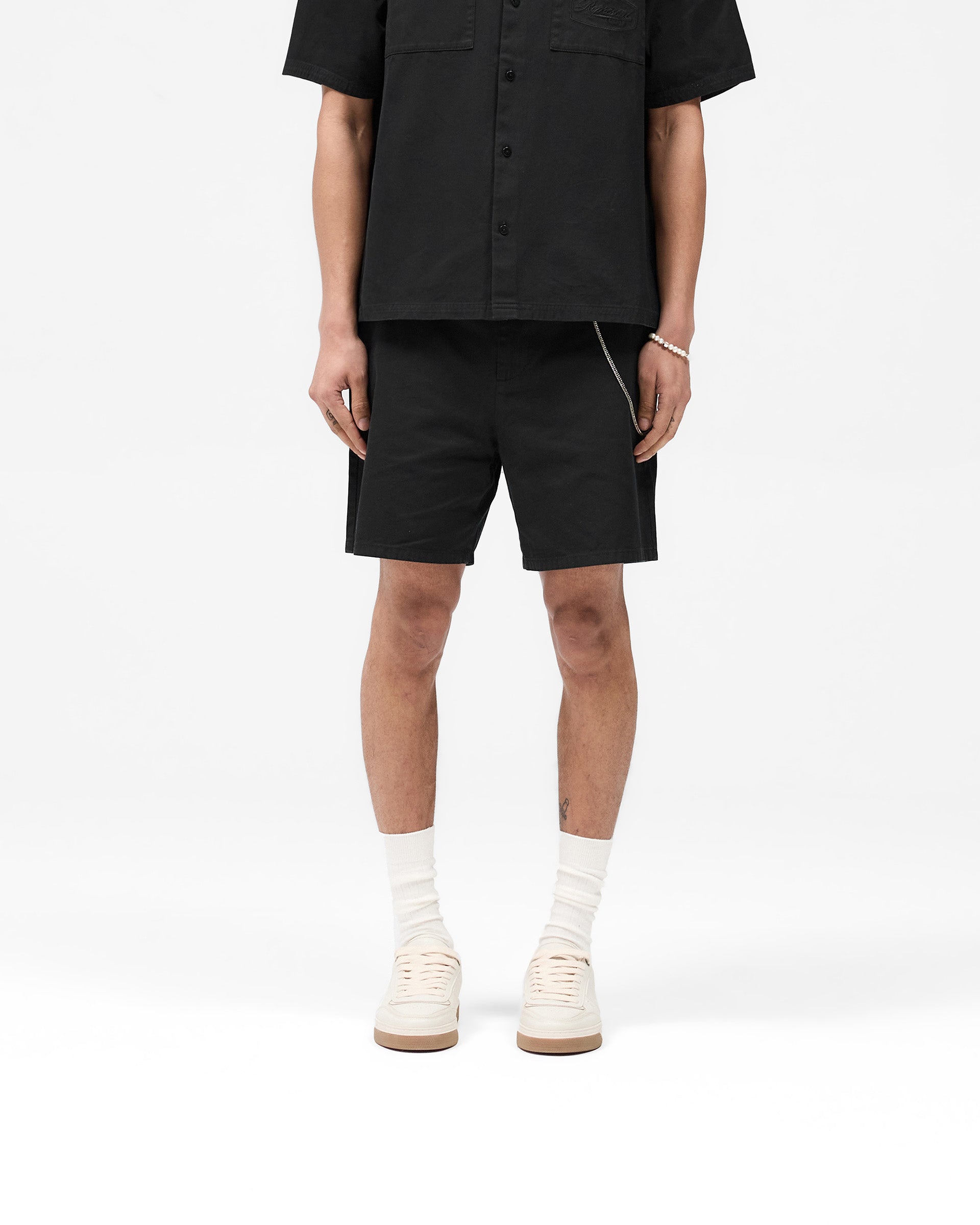 Man wearing black tailored shorts on a plain white background | Cotton Tailored Short in Jet Black | 100% fine twill cotton structured shorts | SS25 Shorts | Represent Clo