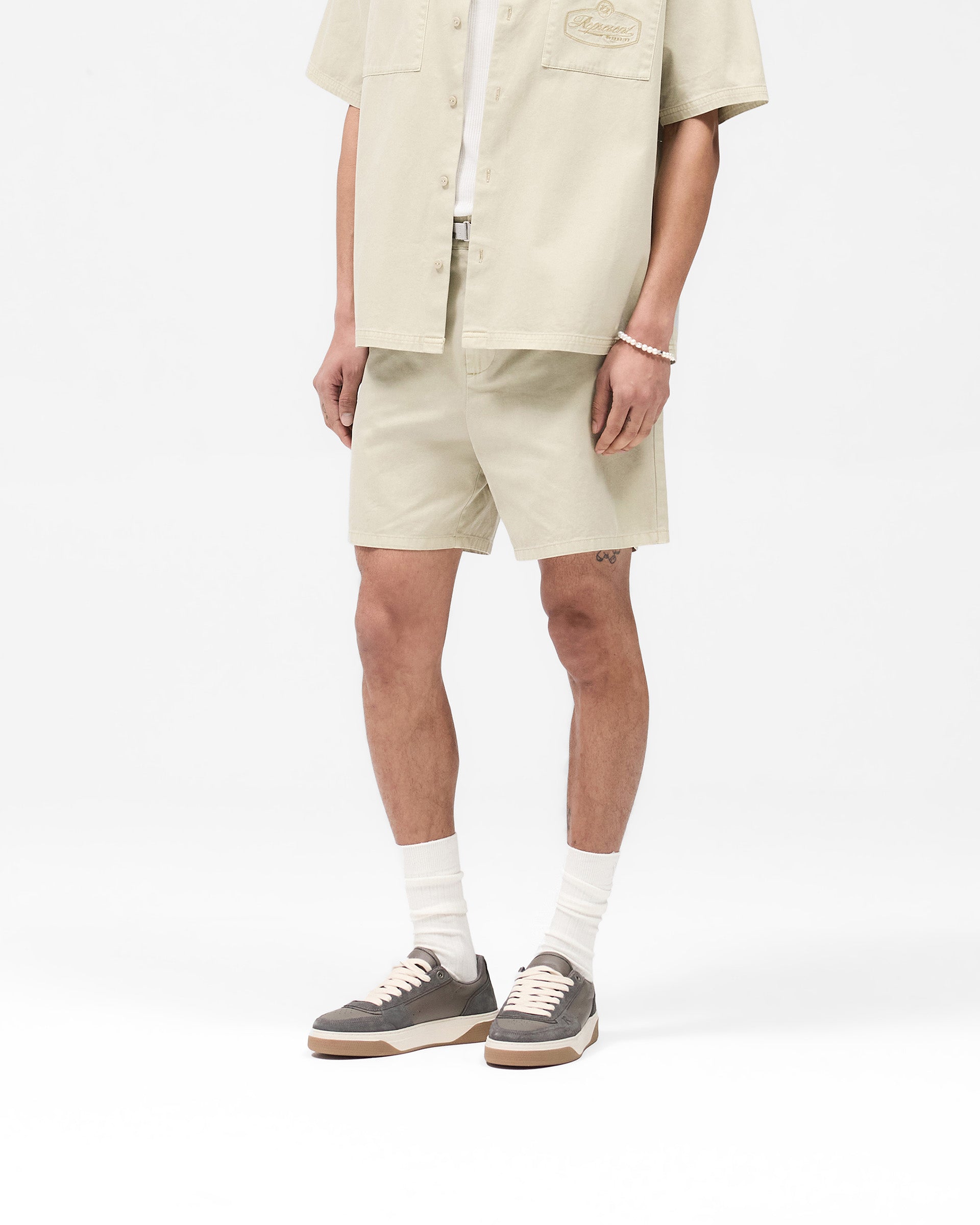 Back product image of mens beige cotton shorts on a plain white background | Cotton Tailored Short in Beige | Structured shorts with tonal embroidery and side pockets | SS25 Shorts | Represent Clo