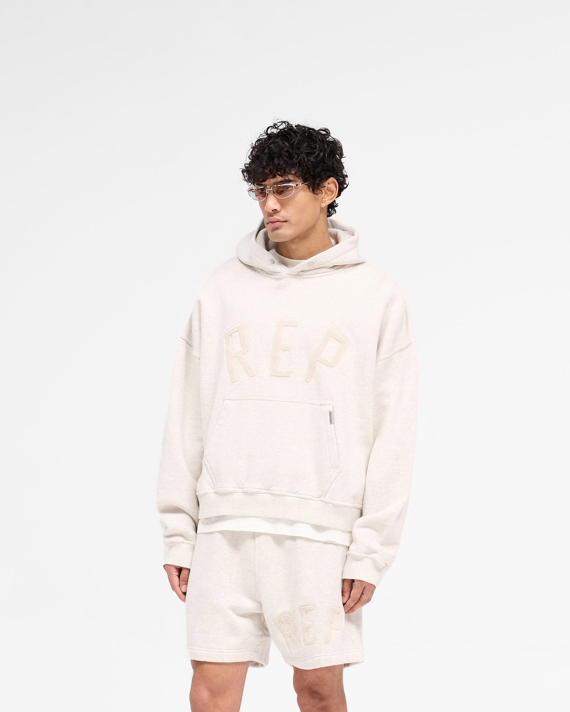 Back product image of a mens cream hoodie on a plain white background | Rep Applique Hoodie in Cream Marl | Boxy fit hoodie with brushed loopback cotton | SS25 Hoodies | Represent Clo