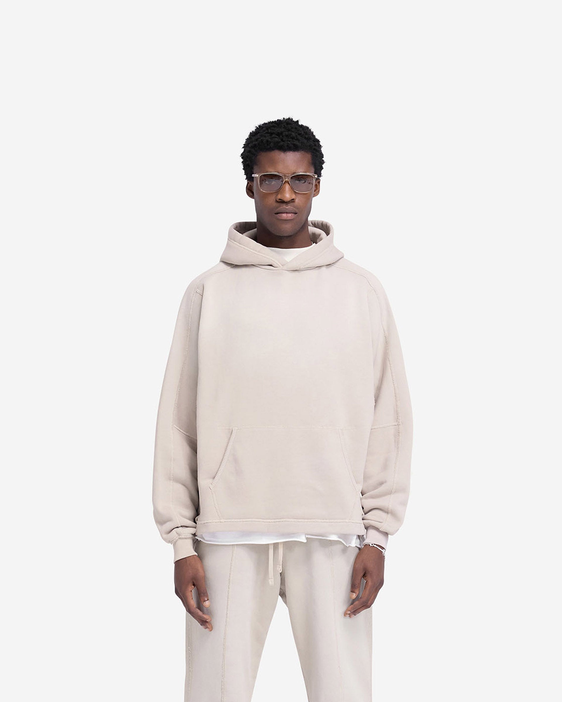 Man wearing an oversized oat hoodie on a plain white background | Stepped Hem Hoodie in Oat | Oversized hoodie with sun fade wash and ribbed trim pocket | FW24 Hoodies | Represent Clo