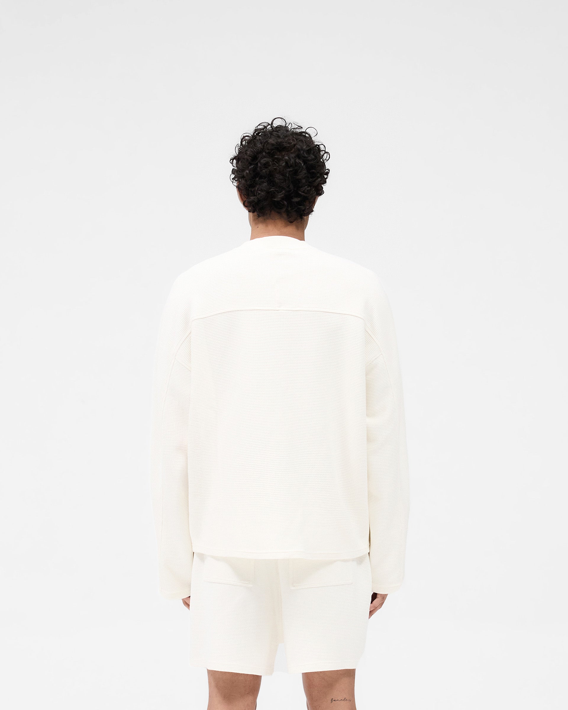 Man wearing a white long sleeve t-shirt on a plain white background | Waffle Long Sleeve T-Shirt in Flat White | Boxy fit t-shirt with interlock waffle fabric | SS25 T-Shirts | Represent Clo