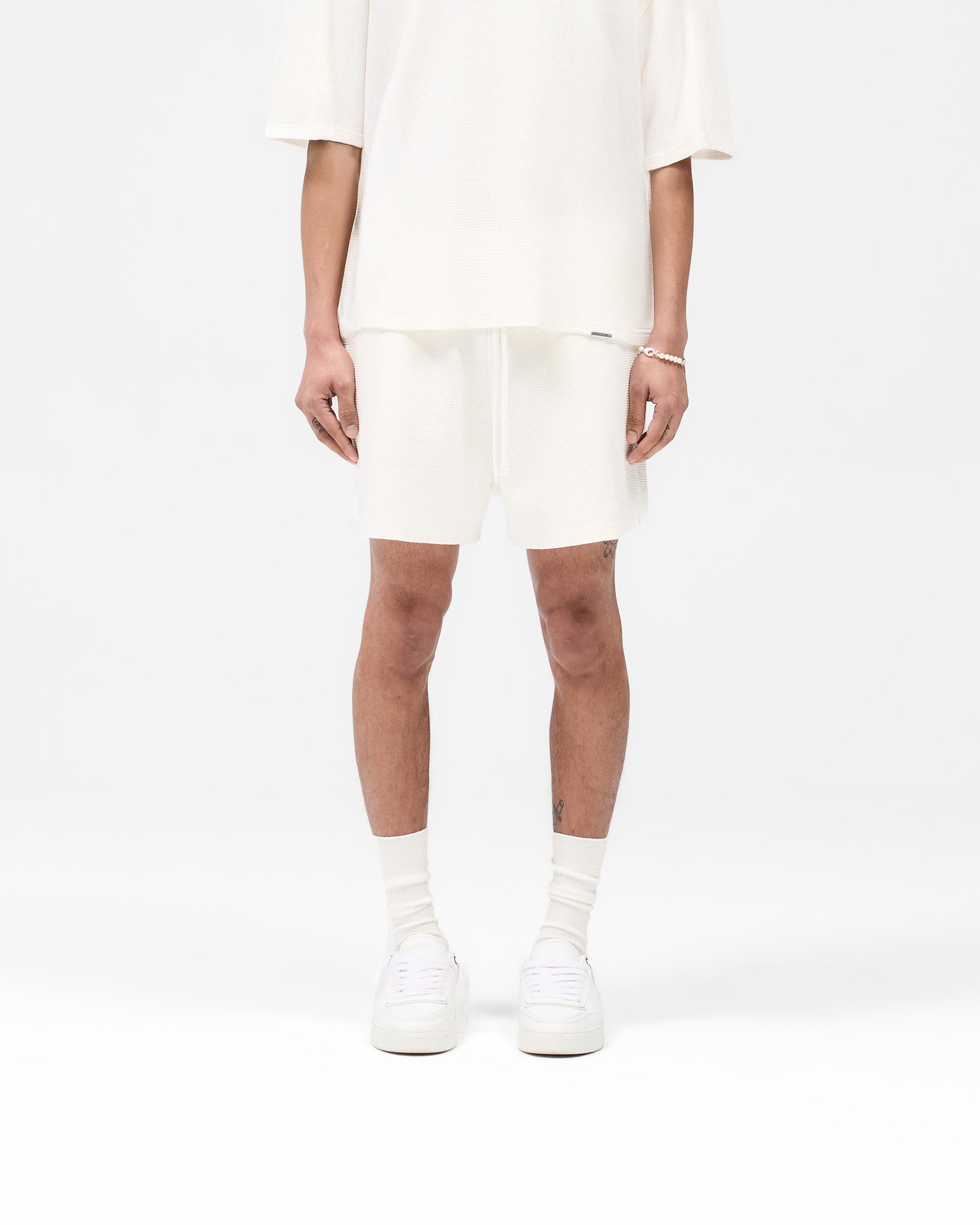 Man wearing white shorts on a plain white background | Waffle Shorts in White | Heavyweight waffle fabric shorts with elasticated waistband | SS25 Shorts | Represent Clo