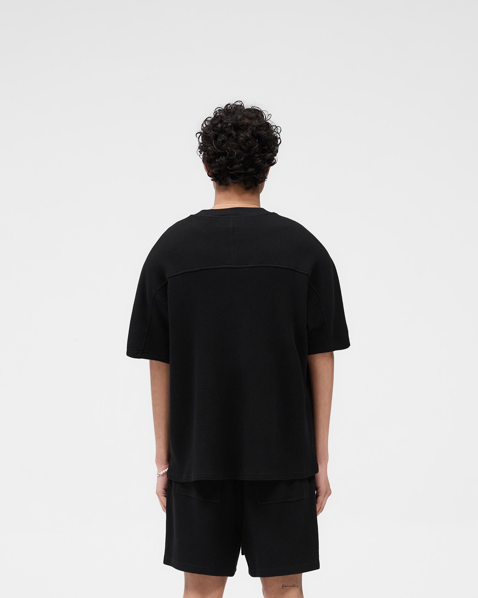 Man wearing a black waffle t-shirt on a plain white background | Waffle T-Shirt in Jet Black | Boxy fit t-shirt with interlock waffle fabric | SS25 T-Shirts | Represent Clo