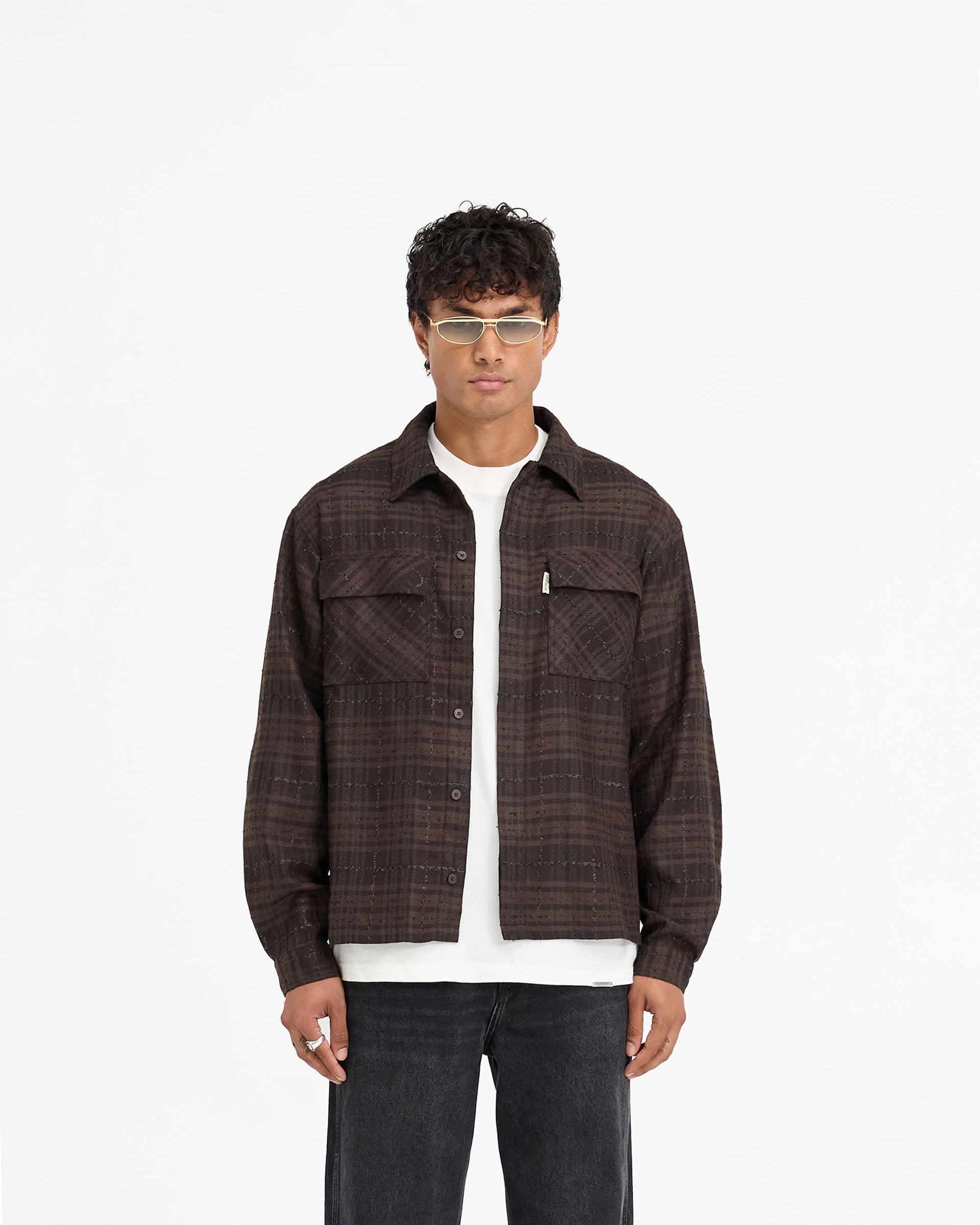 Man wearing a brown flannel shirt on a plain white background | Rep Flannel Shirt in Coffee | Slightly oversized shirt with flap chest pockets | FW24 Shirts | Represent Clo