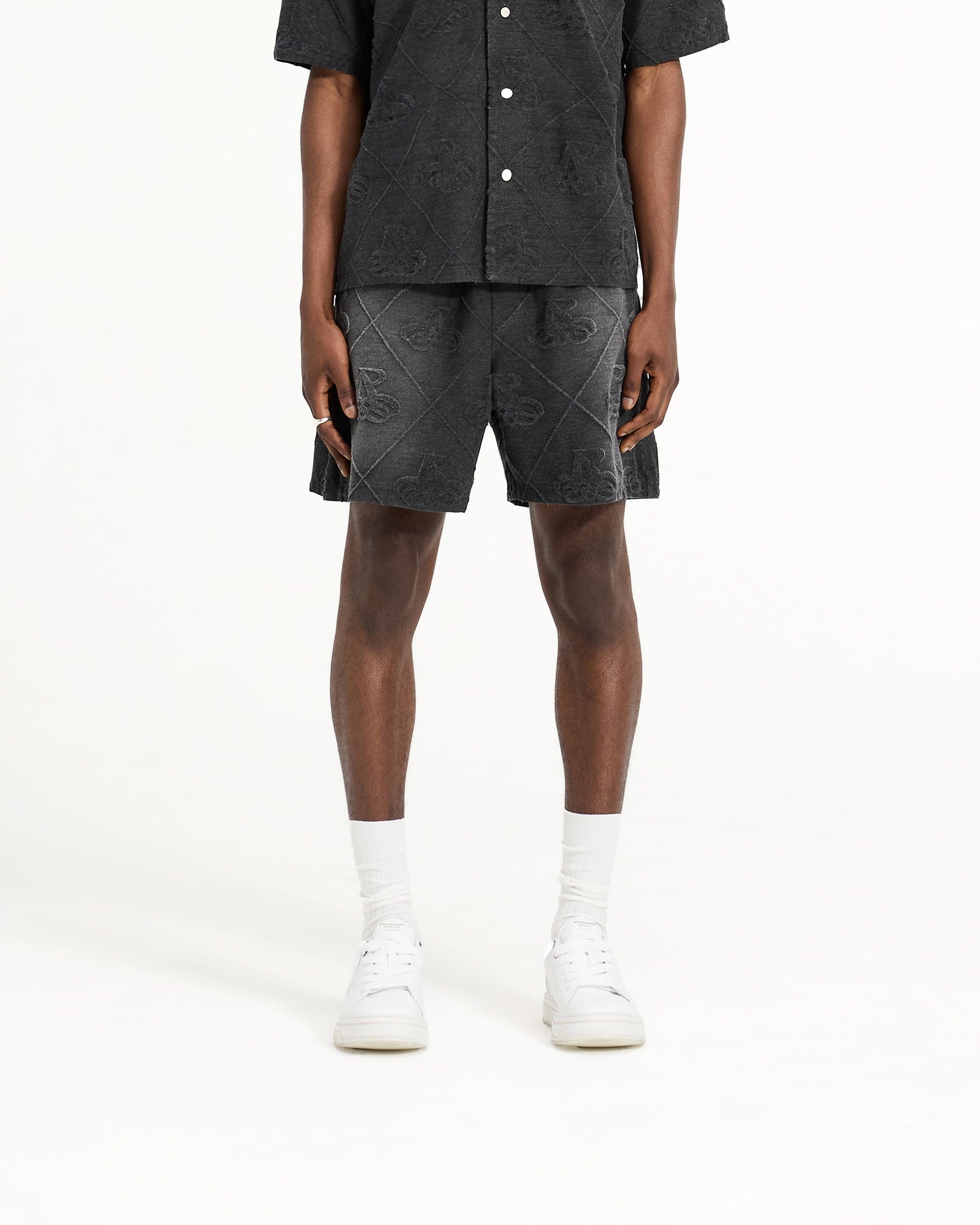Man wearing black towelling shorts on a plain white background | Towelling Short in Jet Black | Relaxed fit shorts with elasticated waistband and drawcord | SC24 Shorts | Represent Clo
