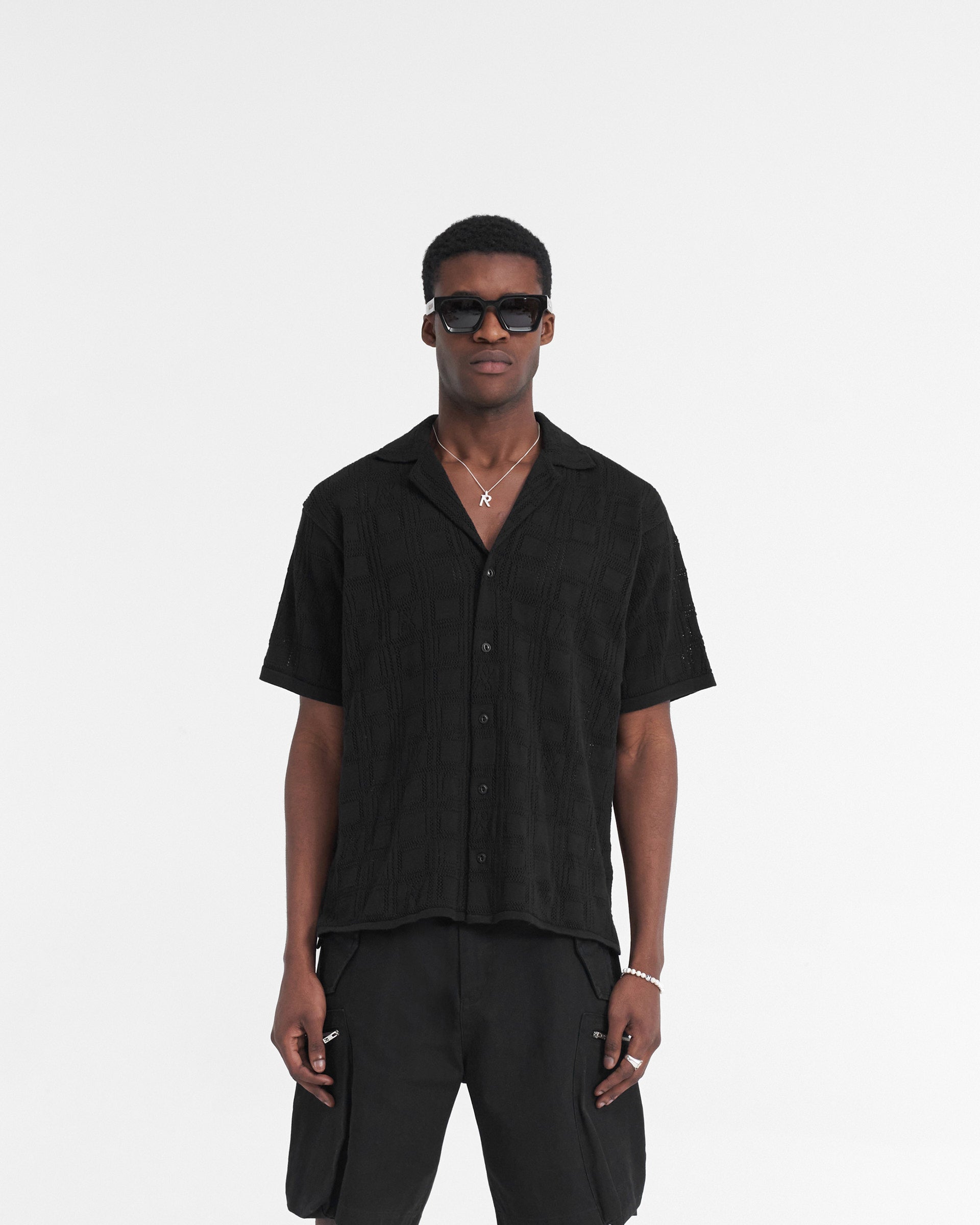 Man wearing a black lace knit shirt on a plain white background | Lace Knit Shirt in Black | Oversized fit with crochet pattern and revere collar | SS24 Shirts | Represent Clo