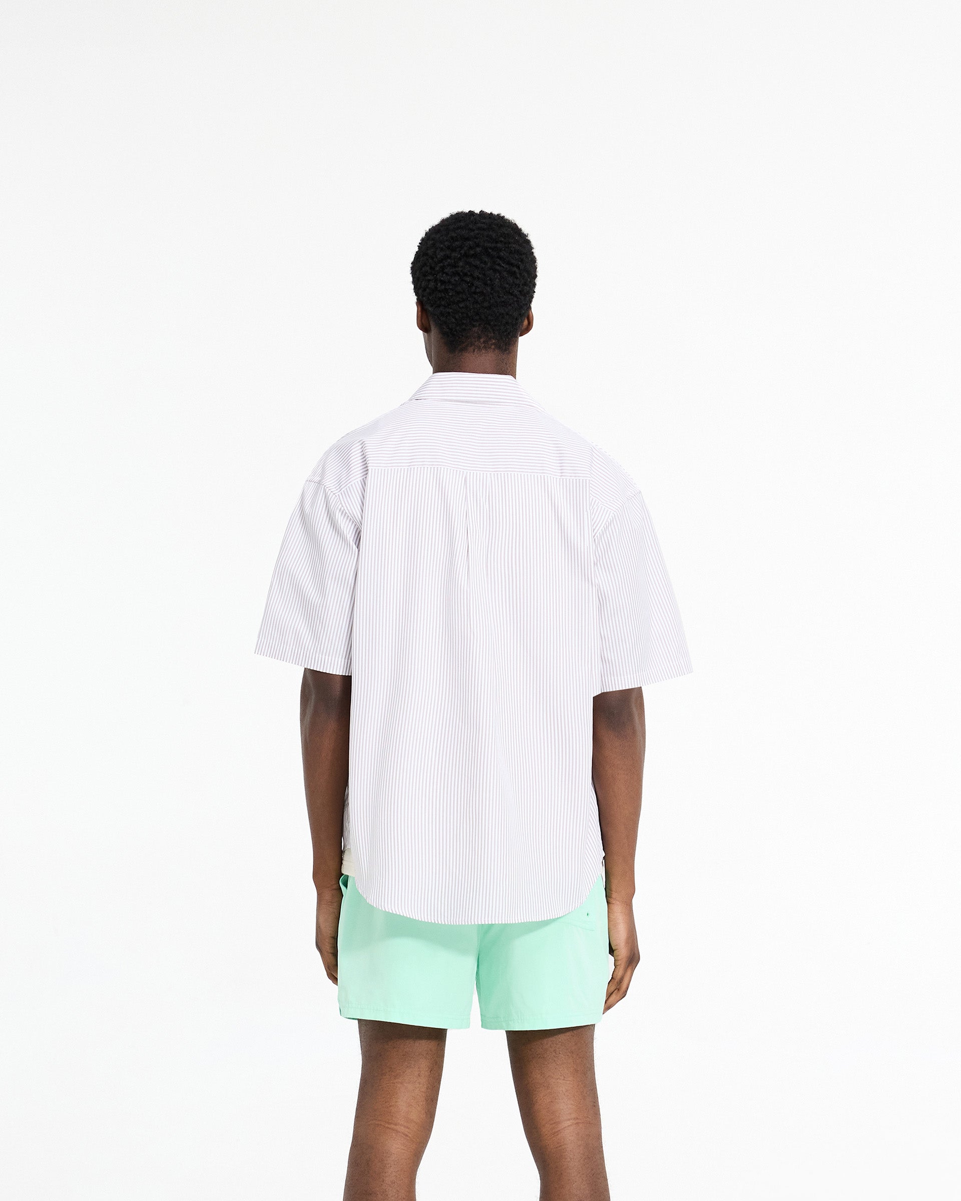 Man wearing a grey pinstripe short sleeve shirt on a plain white background | Short Sleeve Pinstripe Shirt in Grey | Slightly oversized shirt with chest pockets | SC24 Shirts | Represent Clo