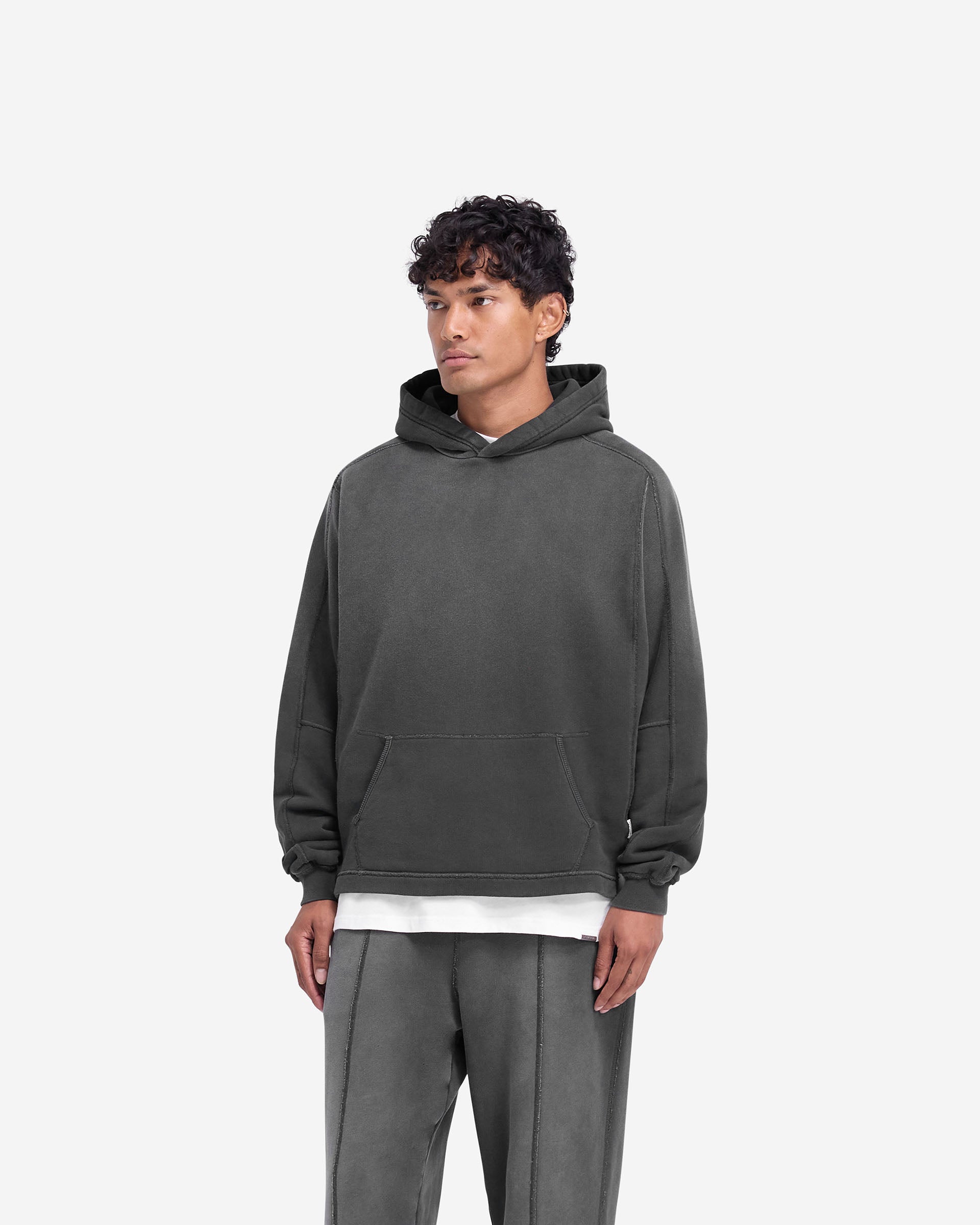 Man wearing an oversized black hoodie on a plain white background | Stepped Hem Hoodie in Stained Black | Hoodie with fade out wash and stepped hem | FW24 Hoodies | Represent Clo